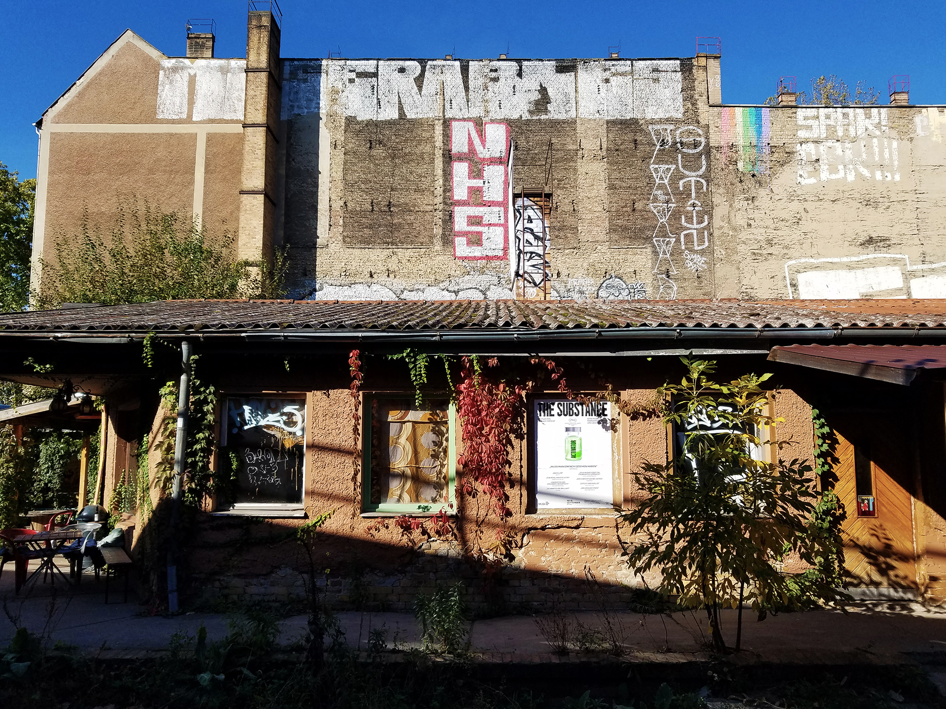 Neue Zukunft venue exterior, an ivy-covered building with a large graffiti mural