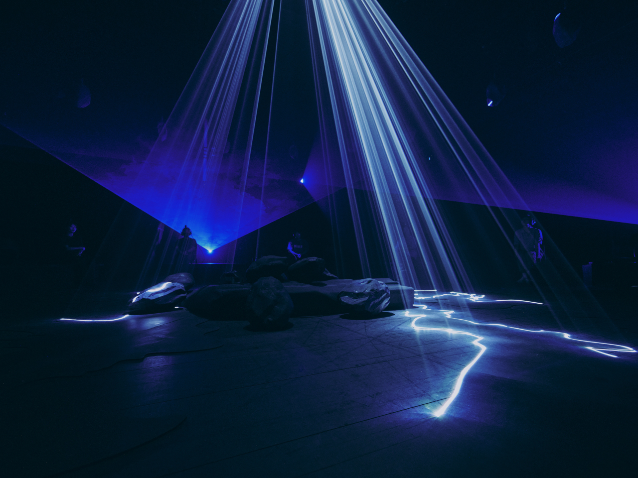 Blue laser beams converging over a rock formation in the immersive theatre piece Underground